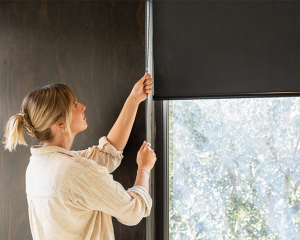 Woman adjusting a roller blind on a window